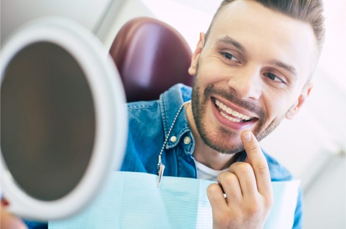 The patient looks at his teeth in the mirror.